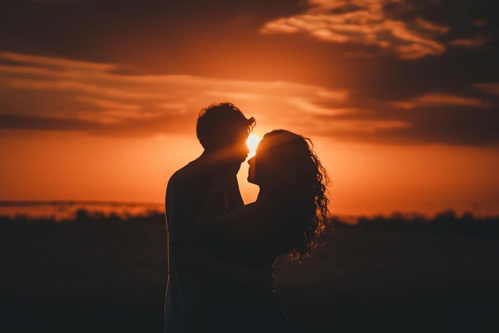 Silhouette of a couple embracing at sunset, illustrating the intensity of passionate love compared to the stability of companionate love.